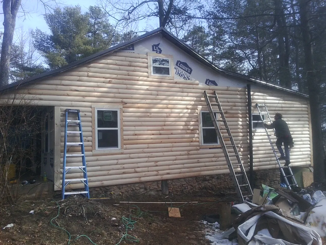 Ladders set against fresh log siding during an exterior remodel in San Diego