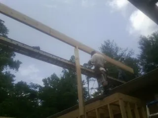 Carpenter setting a ridge beam over a new addition frame — Ice Dam Removal by Roofing Brothers in San Diego