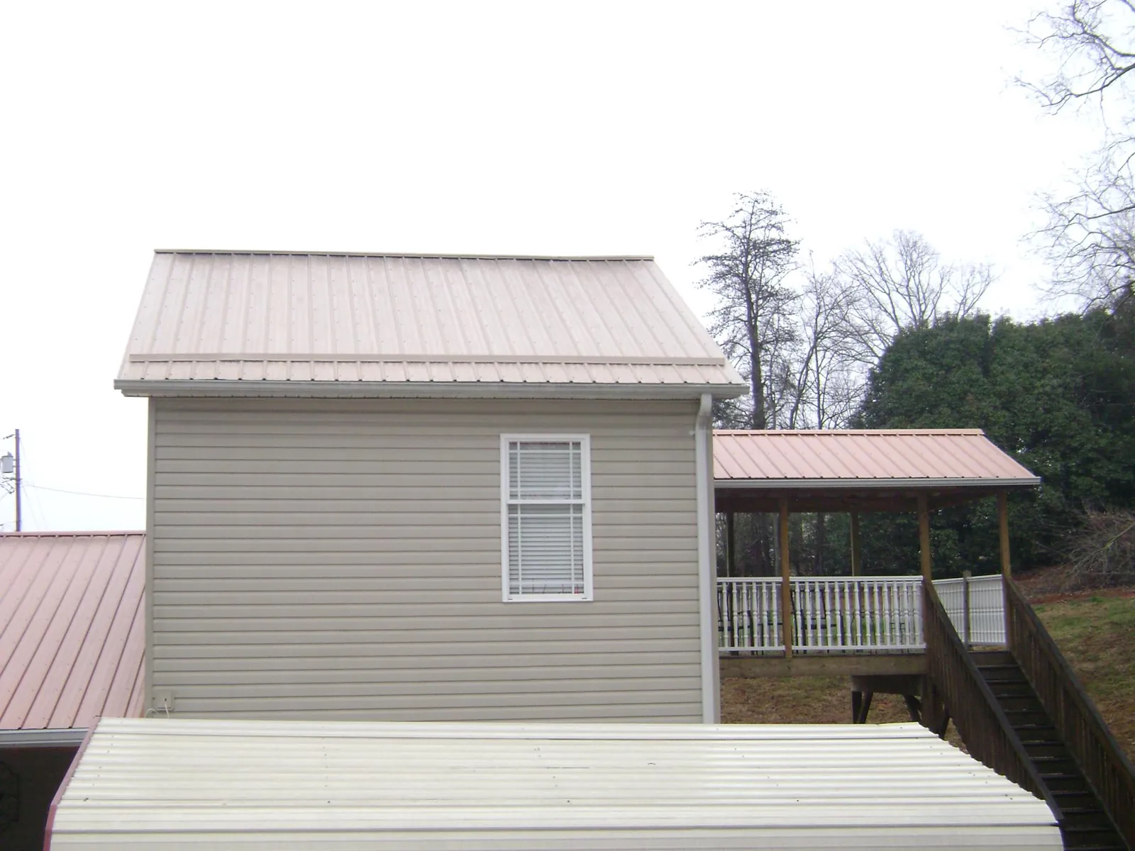 Tan metal roofs on a two story addition and attached porch, from a Roof Replacement job in San Diego