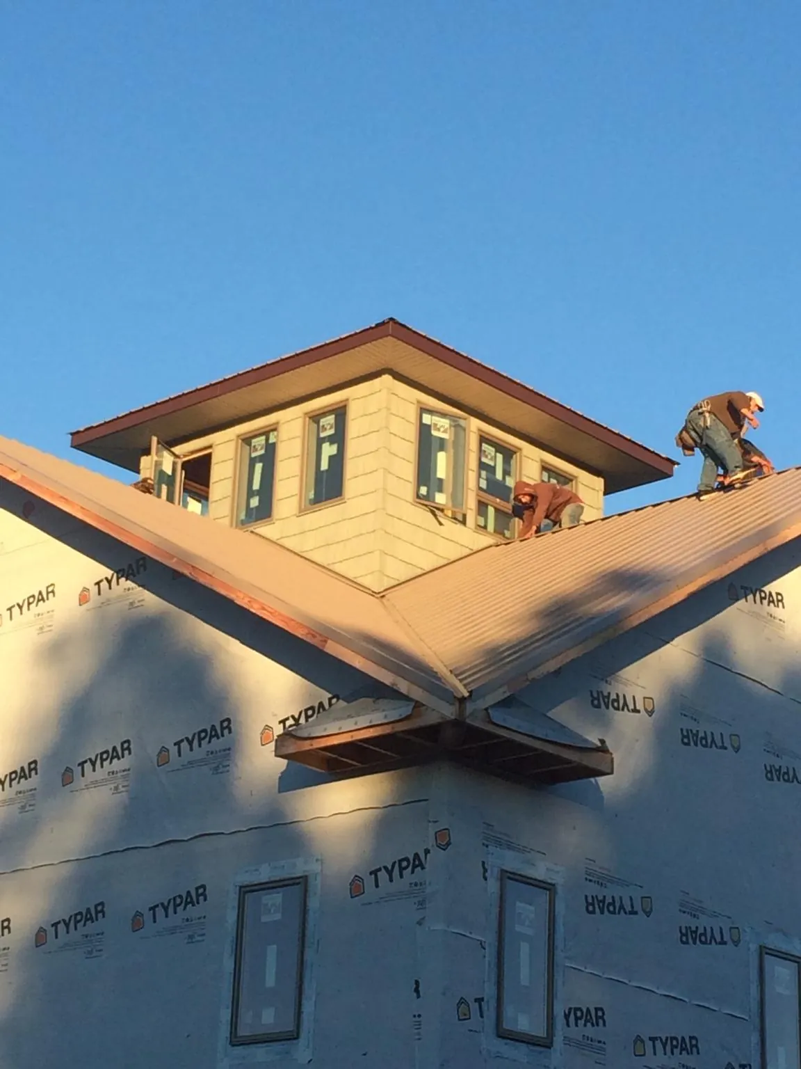 Roofers working around a rooftop cupola on a new metal roof at sunset — Roof Waterproofing in San Diego by Roofing Brothers